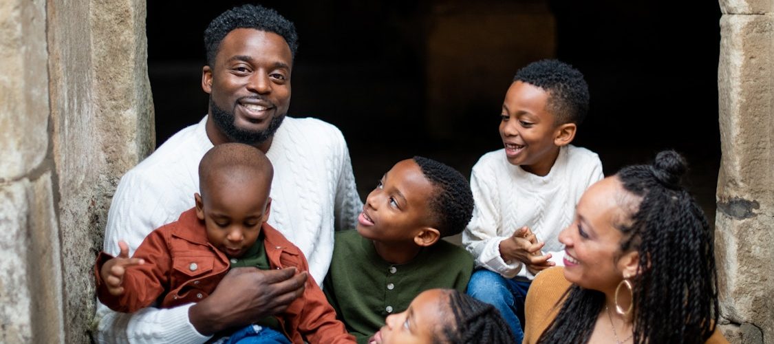 An African American family of six with a mom, dad, and several kids of various ages.