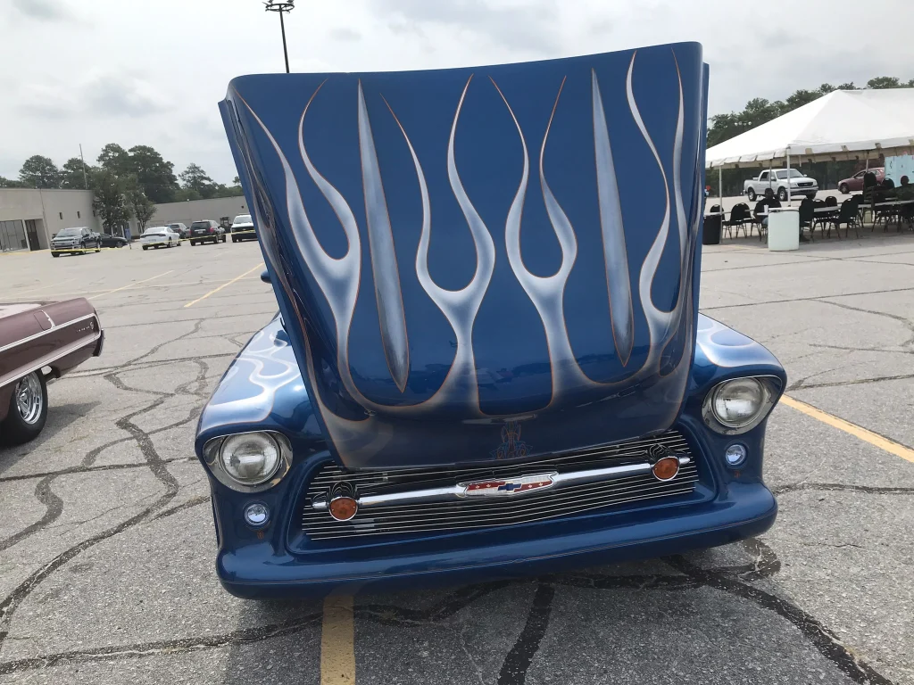 The hood of a blue truck with blue flames painted on it