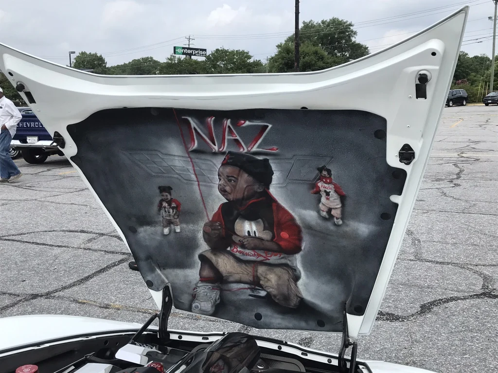 The inside of hood of the car shows a young child painted on it.